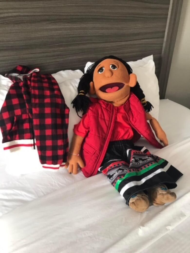 A puppet sits on a hotel bed