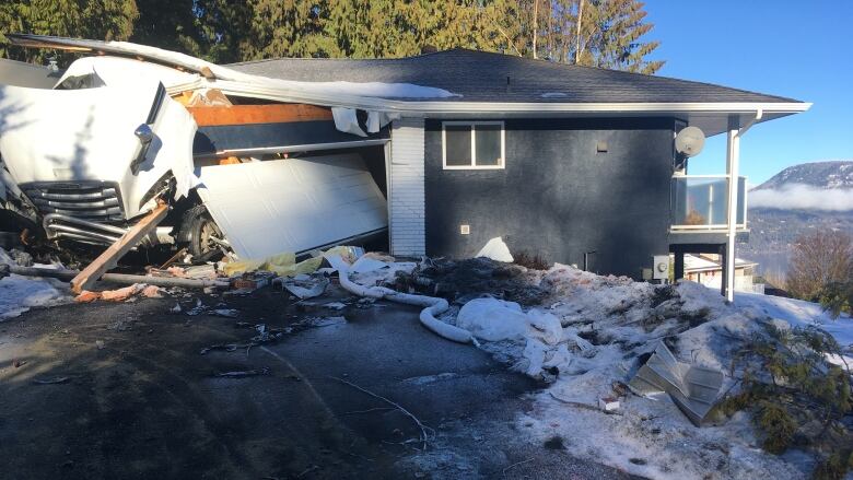 A semi-truck sticks out of the garage of a grey single-storey home.