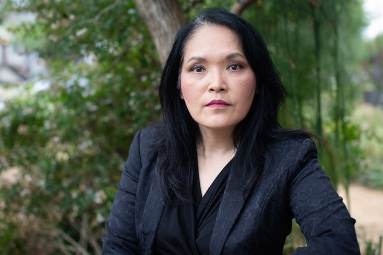 Woman sitting on park bench looking into camera.