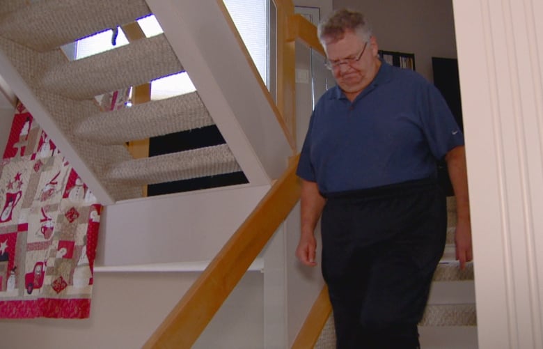 Mike Johansen is pictured walking down a staircase in his home. 