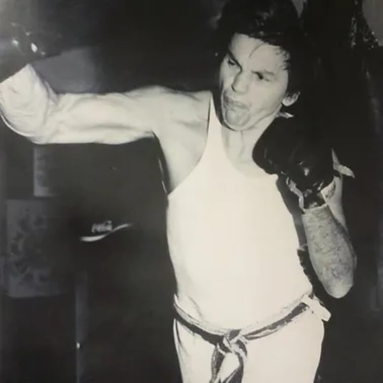 A man wearing boxing gloves throws a punch in this archival photo.