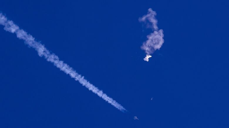 Trails from an aircraft are shown in the sky, along with a white object.