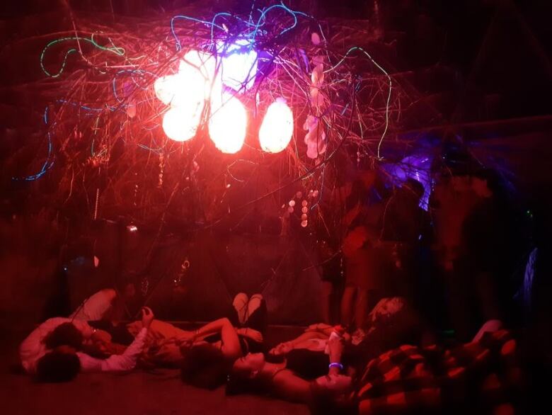 Attendees lie on the grass, underneath a geodesic dome, at the Winnipeg Folk Festival.