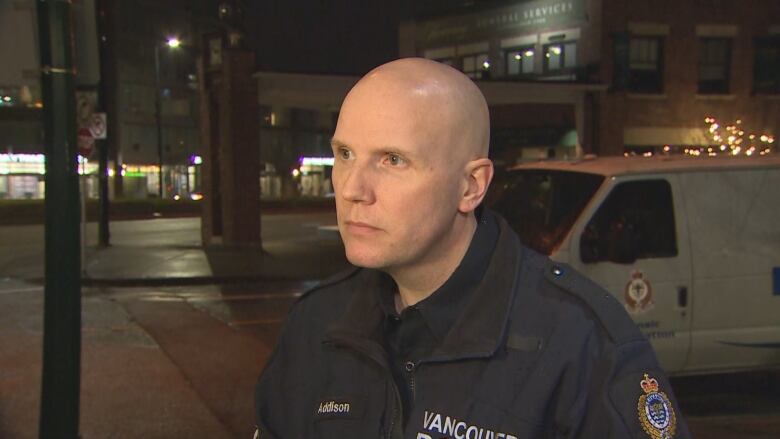 Sgt. Steve Addison stands on a sidewalk at night in a dark blue uniform.