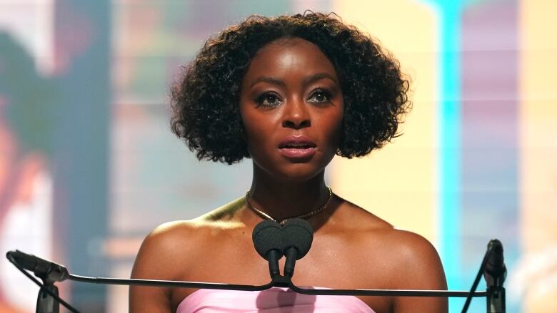 A Black woman standing at a podium speaks into a microphone.