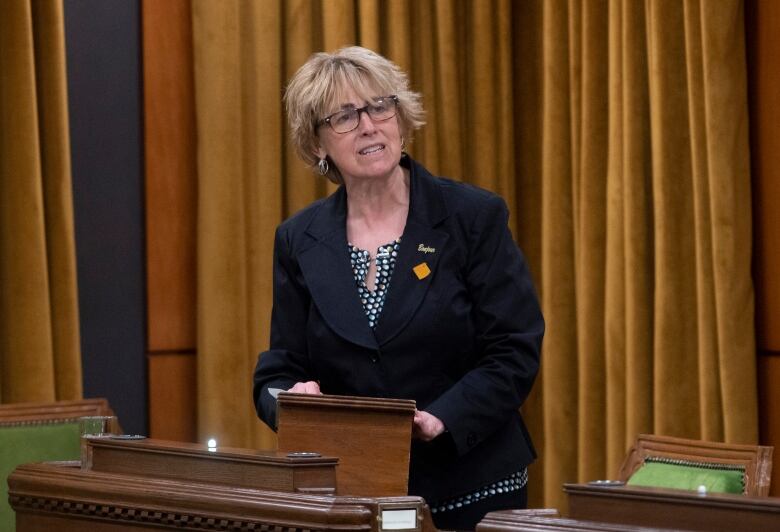 A woman in black stands at a podium.