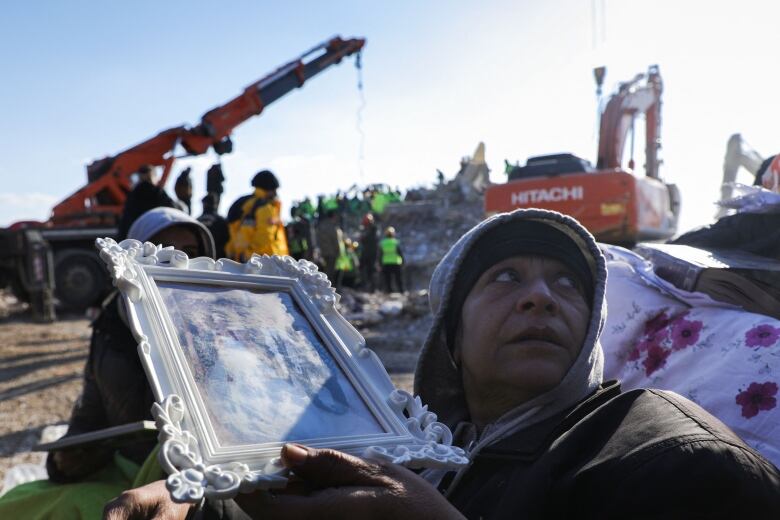 A person holds a photo near a scene of quake-related destruction in Nurdagi, Turkey.