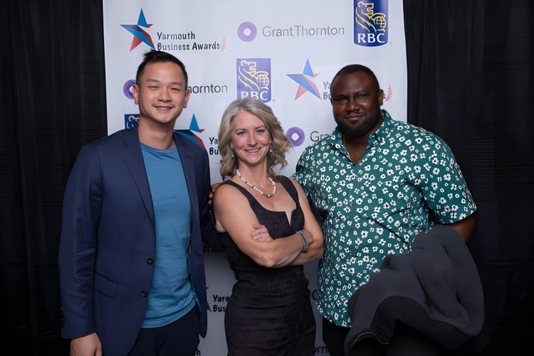 Three people  two men and a woman  smile at the camera at a gala event.