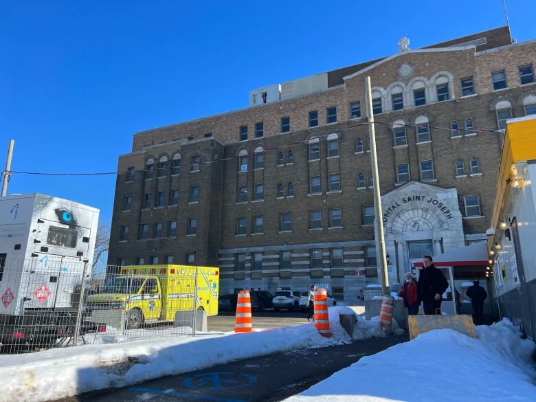 Hospital in winter time, with an ambulance out front.