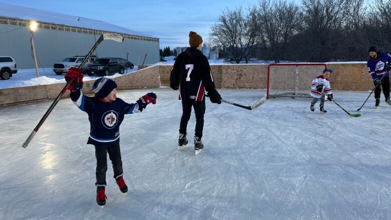 Children and adults play on an outdoor hockey rink.