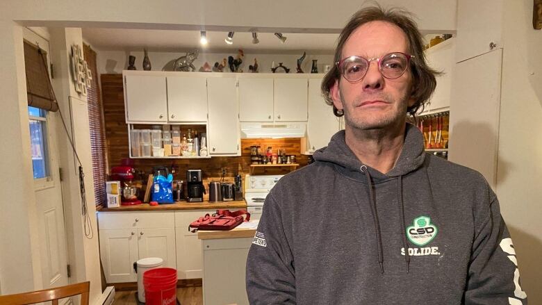 A man stands in his kitchen. 