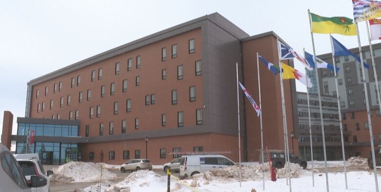 A large brick building with glass entry atriums and flags flying outside.