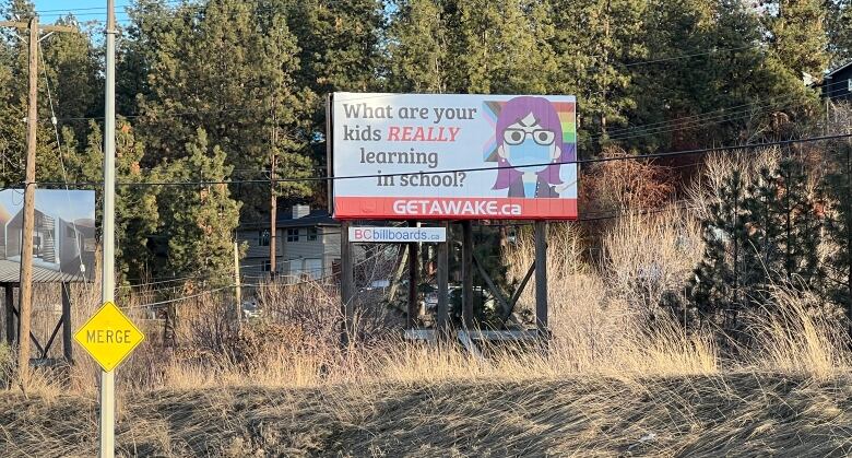 photo shows a billboard with a caricature of a stern teacher wearing a mask and standing in front of a transgender pride flag 