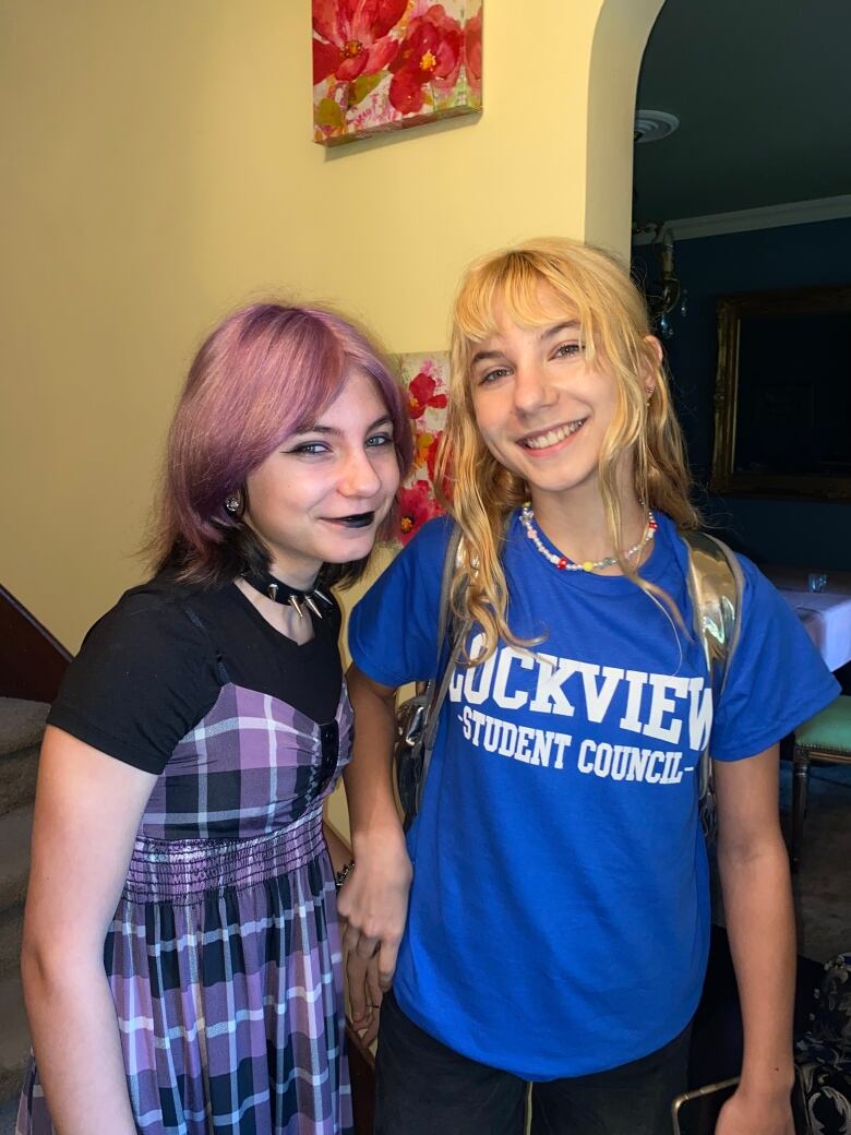 Two young girls are seen smiling together.