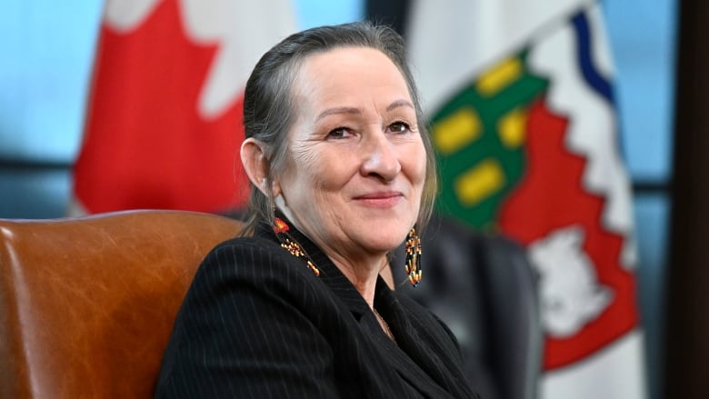 Smiling woman in front of NWT, Canada flags.