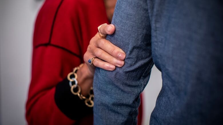 A woman's hand is seen clasping the arm of her son.