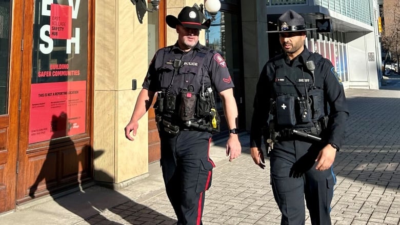 Two officers walk down a street.