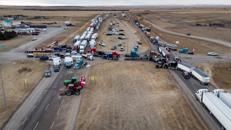 Many cars and trucks are parked on a snowy highway.