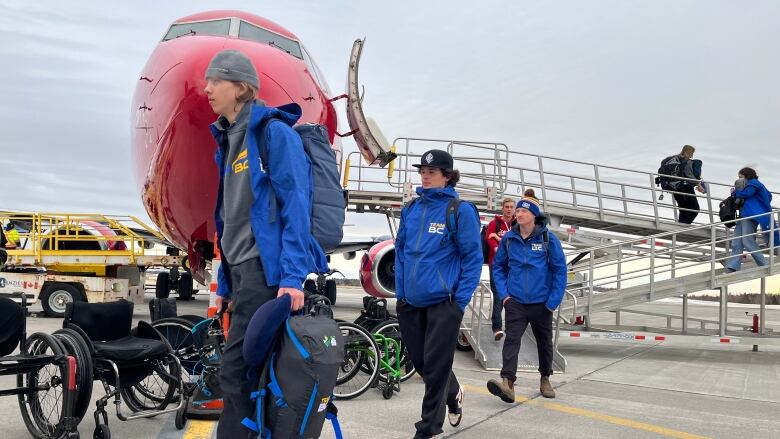 young athletes wearing blue Team B.C. sweaters disembark from a plane