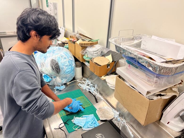 Graduate student Anaamalaai Annamalai Senthilnathan, 24, manually slices up some of the used face masks using a knife.