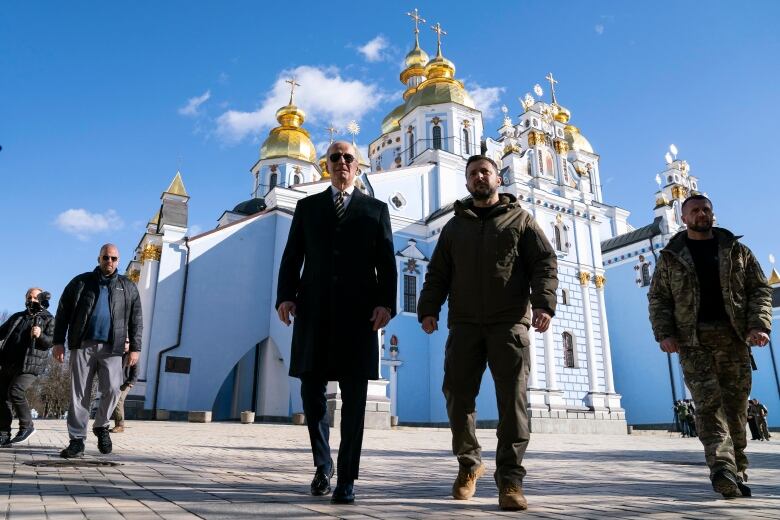 Two men walk in front of a cathedral.