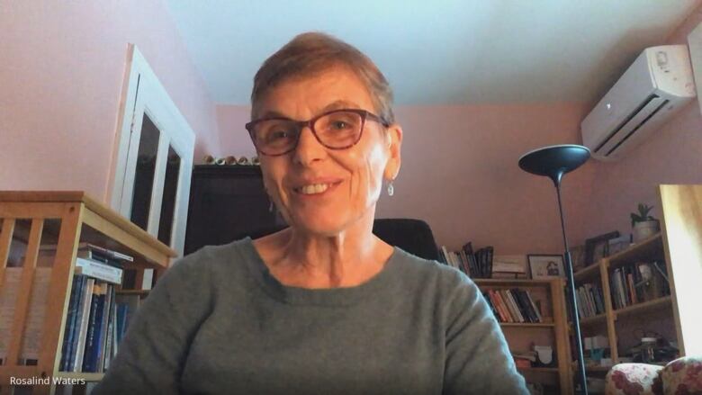 A woman sits indoors and smiles toward the camera