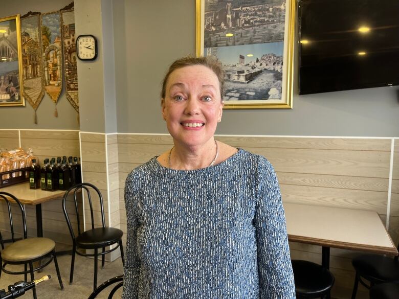 A woman stands in a bakery. 