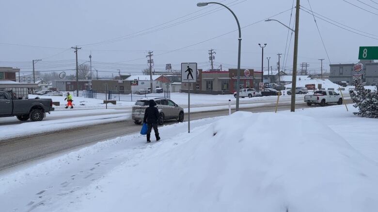 A man walks on a snowy sidewalk.