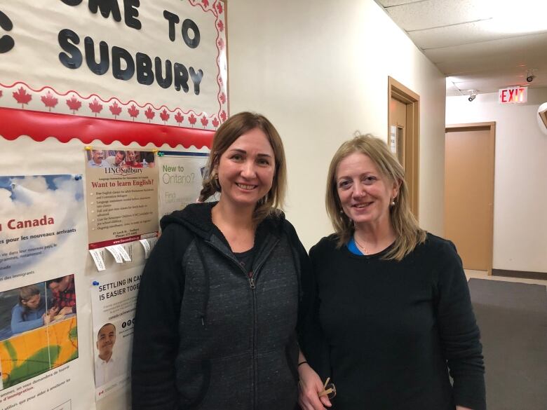 Two women standing in a hallway.