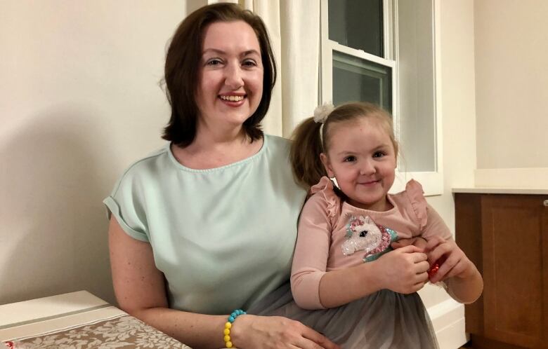 Woman poses with daughter on her lap.