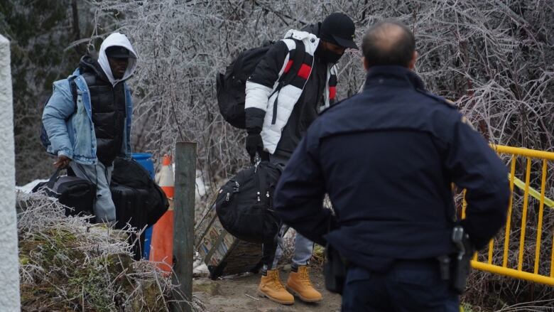 An RCMP officer looks on as asylum seekers cross the Canada-U.S. border at Roxham Road, on Jan. 5, 2023.  