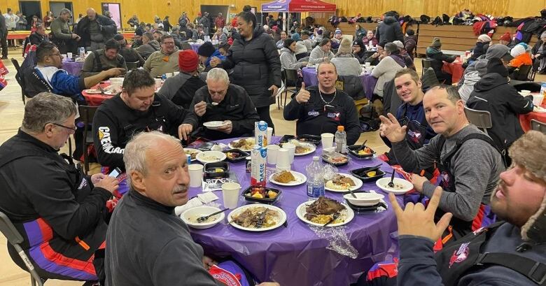 A feast is happening with dozens of people at several tables.