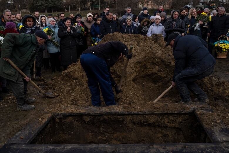 Diggers throw soil onto the grave of 32 year-old soldier Denys Averiiev during a funeral at Lviv cemetery, western Ukraine, on Thursday, Feb. 23, 2023. Averiiev died in Bakhmut on Feb. 16, 2023.