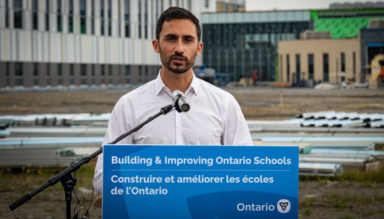 Stephen Lecce at a podium outside a school under construction