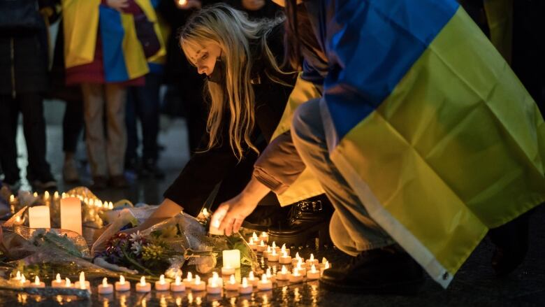 Two young women light candles during a vigil in Tokyo.