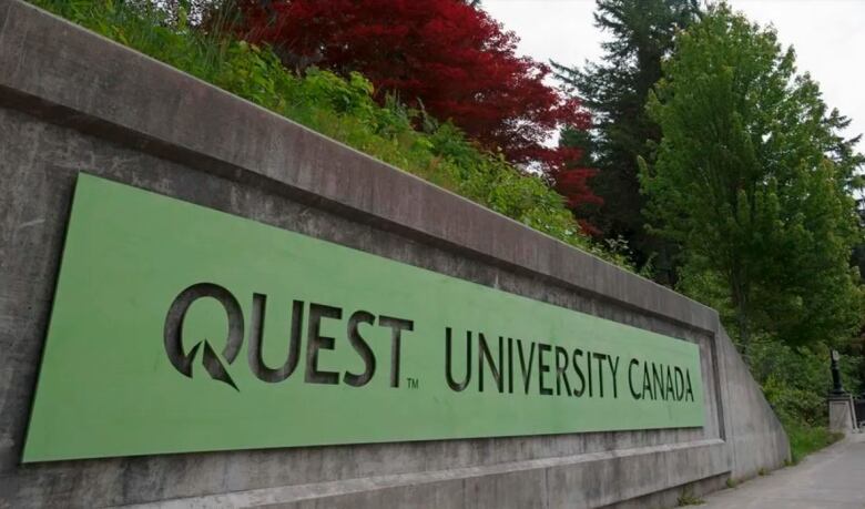 A forest-green sign that says Quest University is shown.