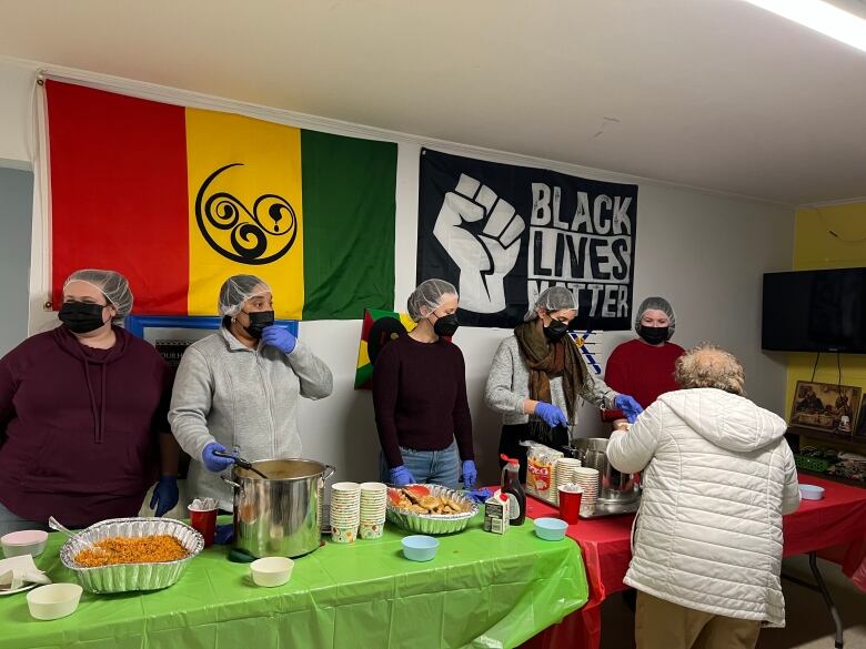 Volunteers and Staff of Mulgrave Park Caring and Learning Centre standing behind the serving table, ready to serve food to community members