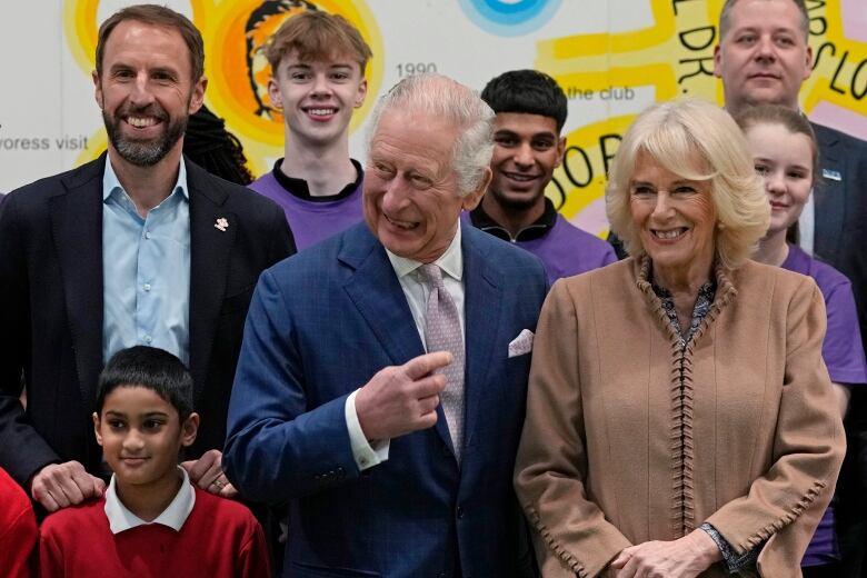 Several smiling adults and youth stand in front of a wall.