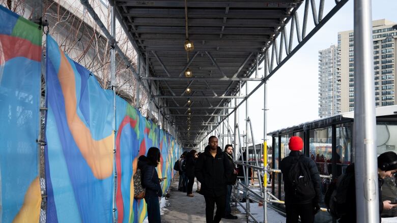 Transit riders at Hurdman station use the scaffolding erected there after the LRT opening in 2019 for protection against the elements.