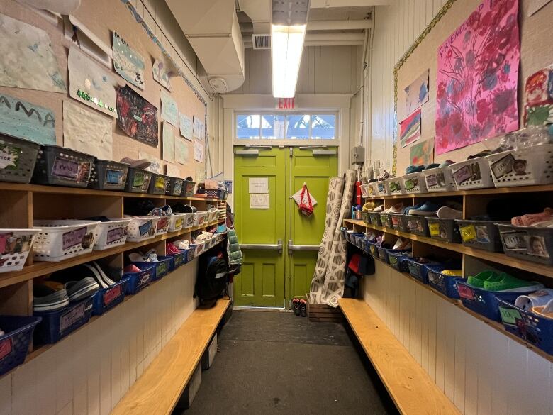 The schoolhouse's interior shows benches and cubbies for kids on either side of a bright green door. 