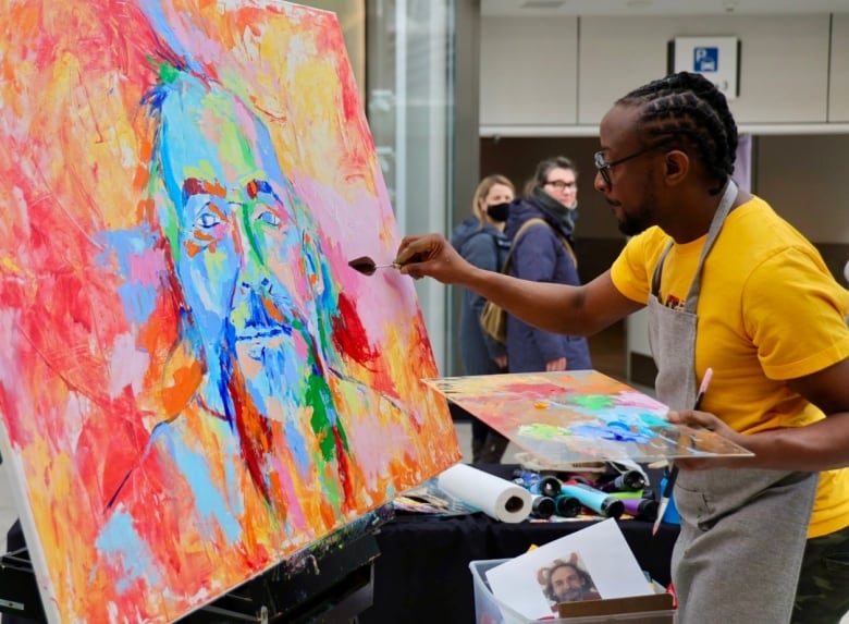 Onlookers walk past Boma Nnaji in the Halifax Shopping Centre as he paints a portrait of Eddie Carvery on Saturday. 