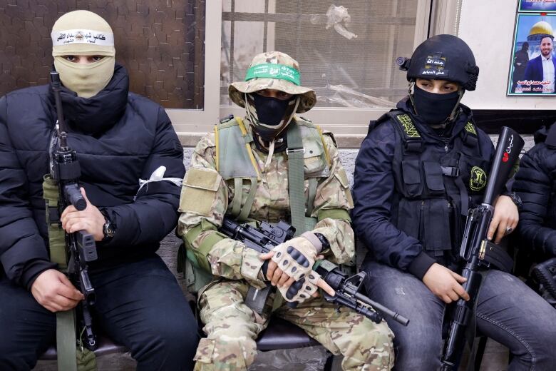 Three Palestinian gunmen are shown sitting together at a meeting.