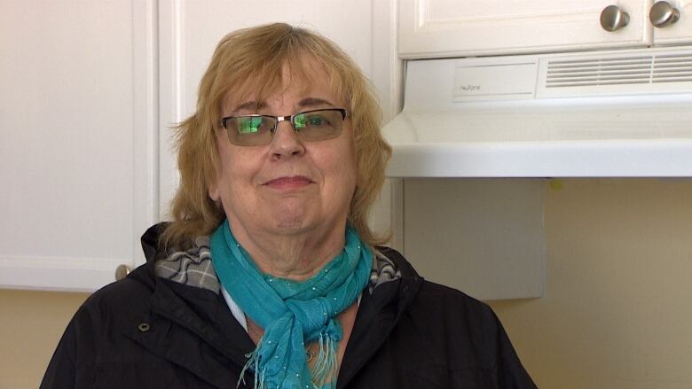 Woman with tinted glasses standing in apartment kitchen