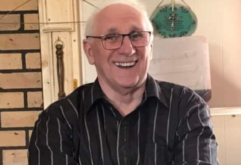 A person wearing a striped shirt crossed his arms while smiling.