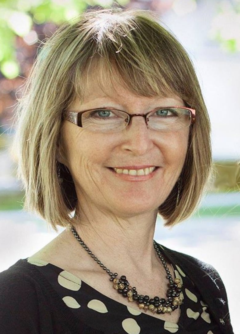 A middle-aged woman with glasses and blonde bob smiles directly at the camera in a professional-looking headshot.