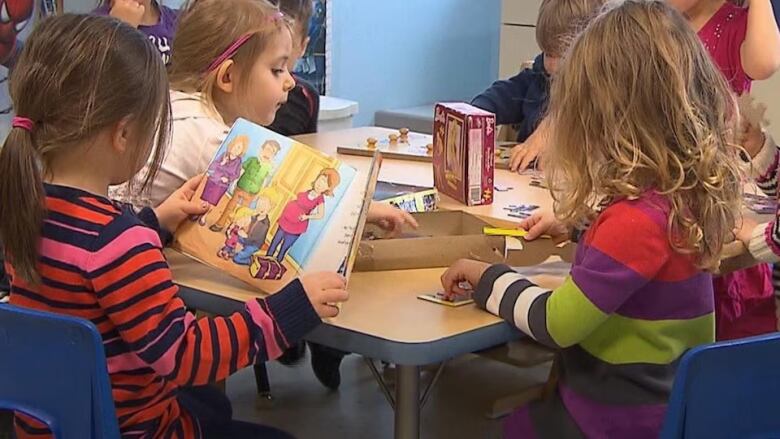 Children read and play at a table. 