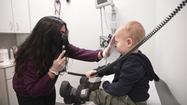 A doctor sees a toddler in an examining room. 