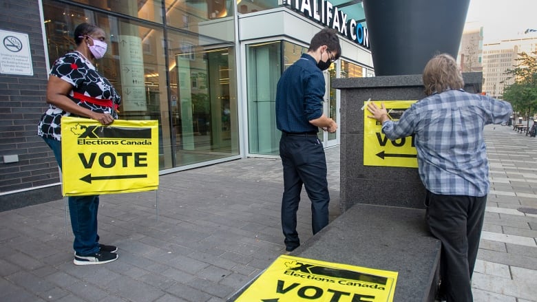 Elections Canada workers place signage at the Halifax Convention Centre as they prepare for the polls to open in the federal election in Halifax on Monday, Sept. 20, 2021.