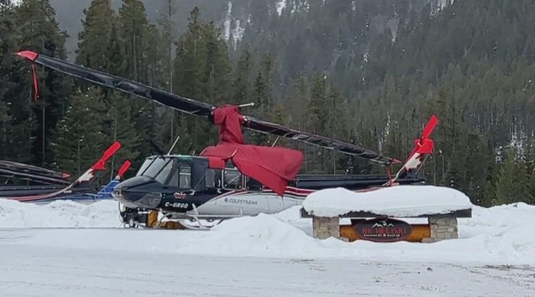 A black and red helicopter sits in the snow.