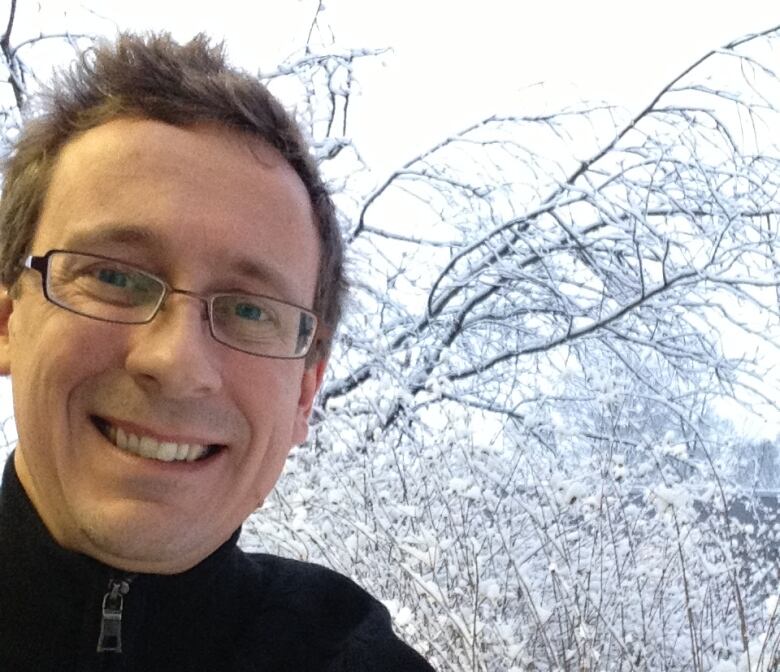 Dr. Robert McLeman smiling as he stands in front of a thin tree with snow covering it